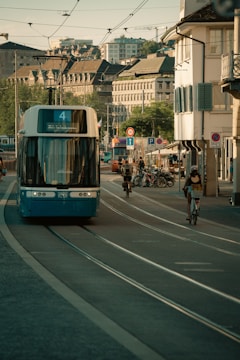 A blue tram moves through a city street.
