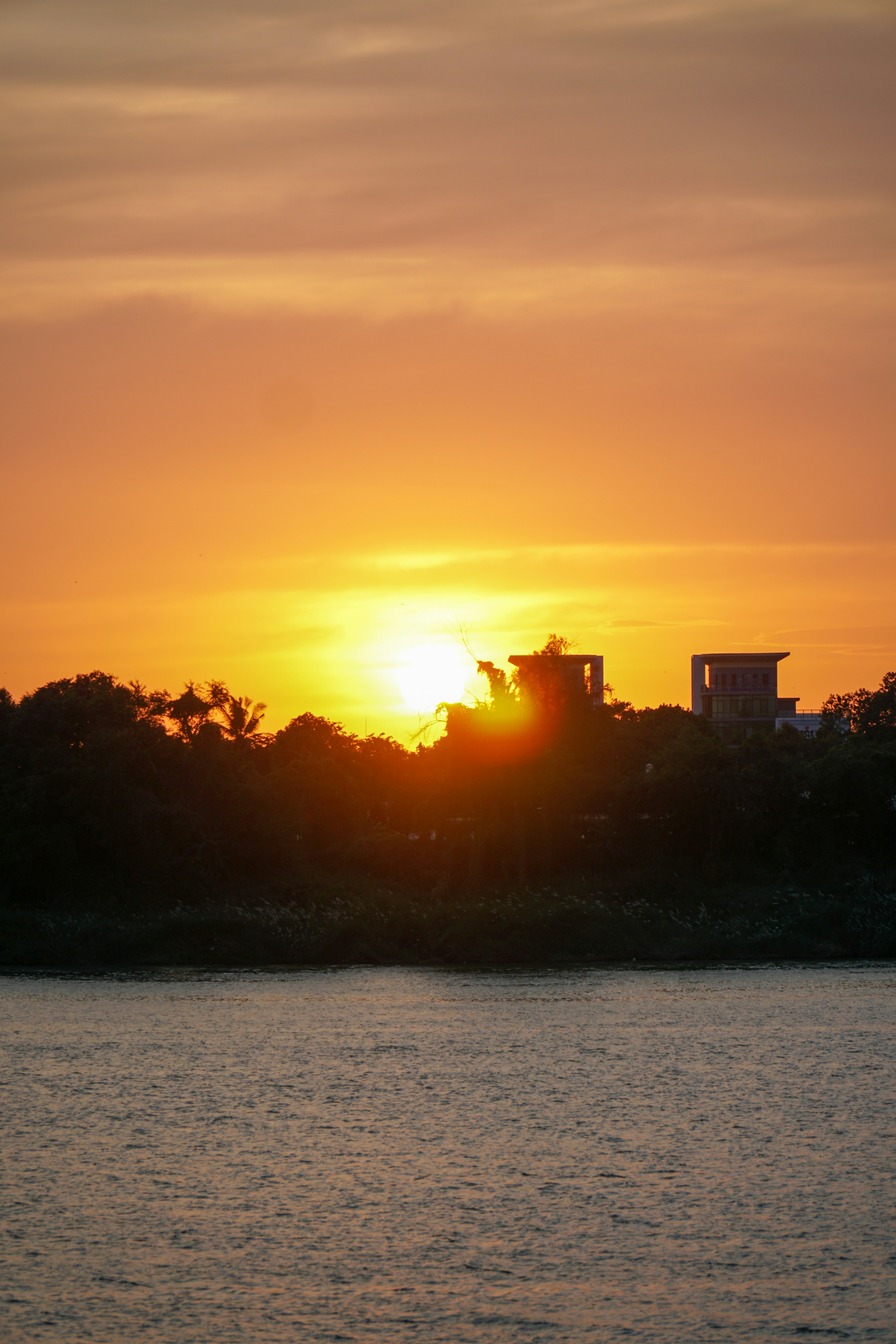 Sunset over a river, with buildings in silhouette.