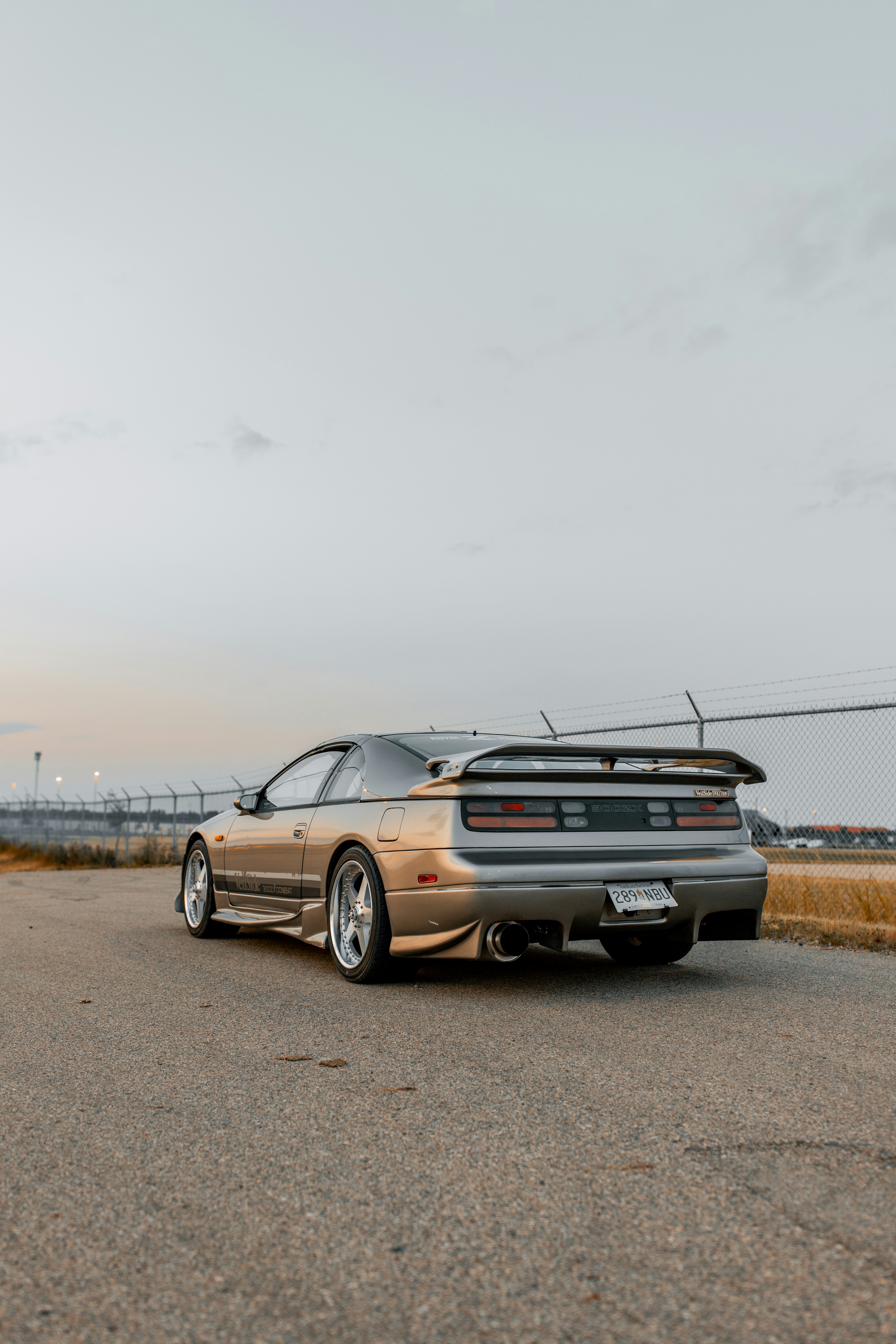 A silver sports car drives down the road.