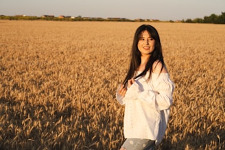Woman smiles in a golden wheat field.
