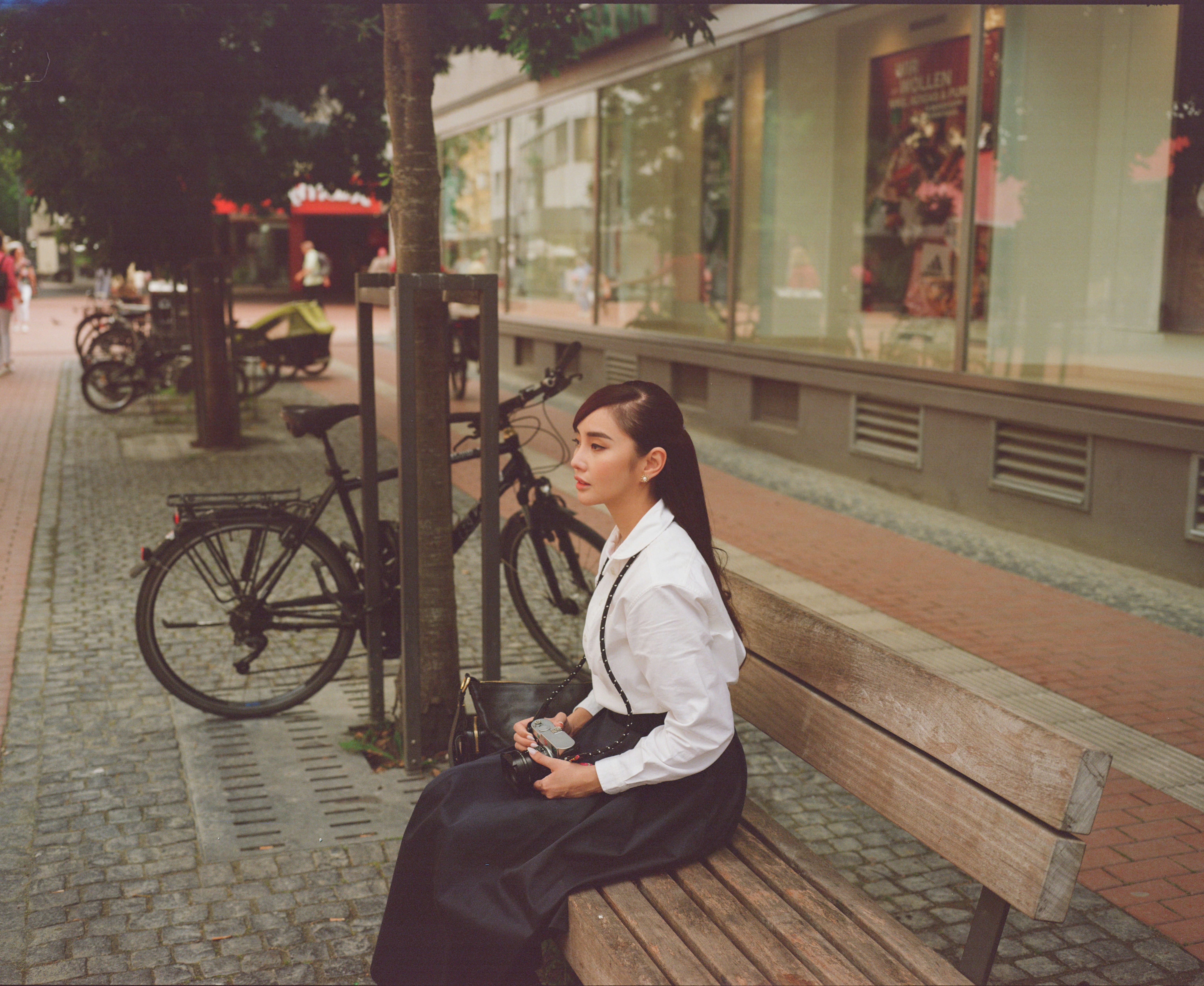 A woman sits on a bench, looking away.