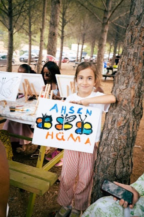 A girl proudly shows off her butterfly painting.