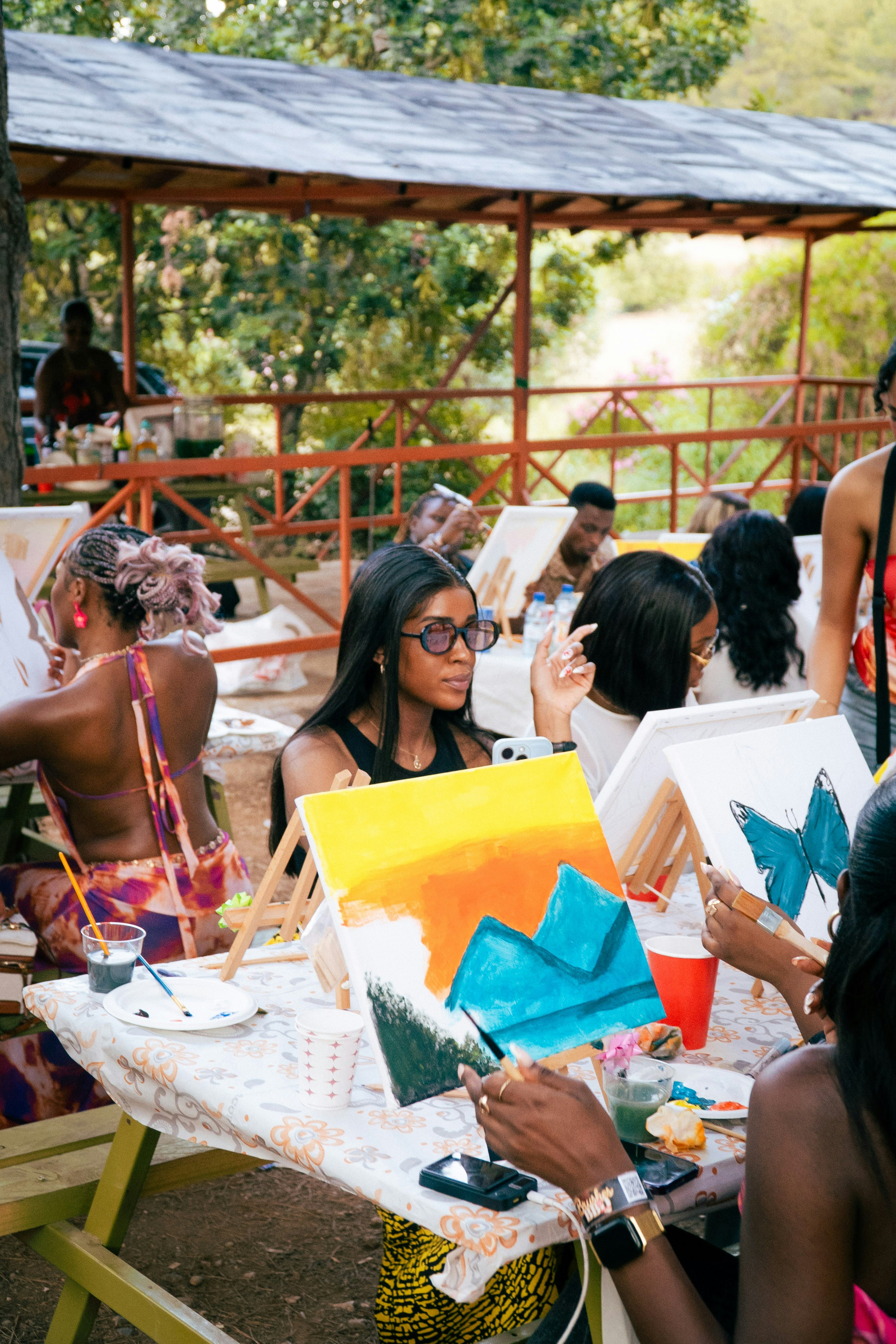Young Black women painting outdoors at picnic tables.