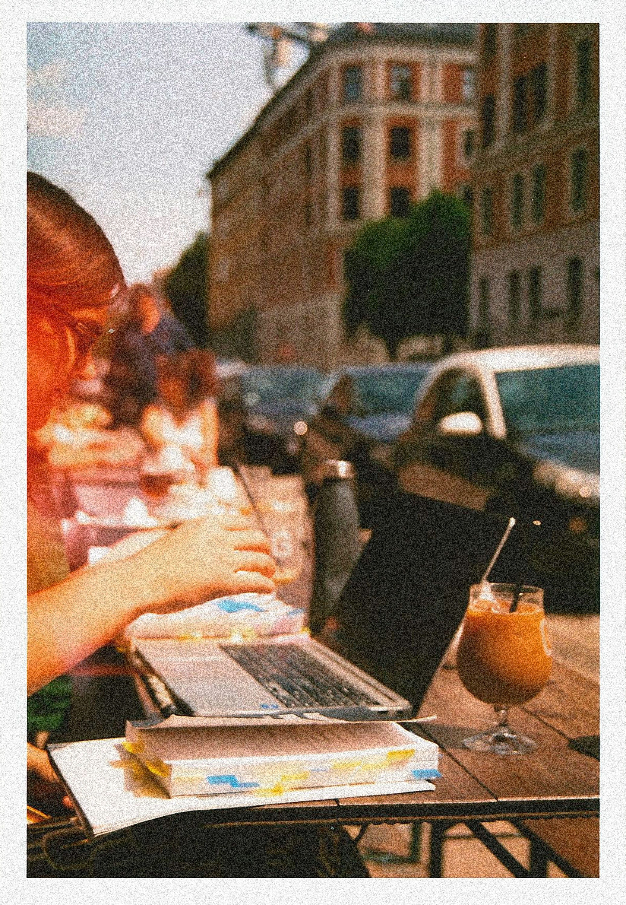 Close-up of hands typing on a laptop with a notebook nearby
