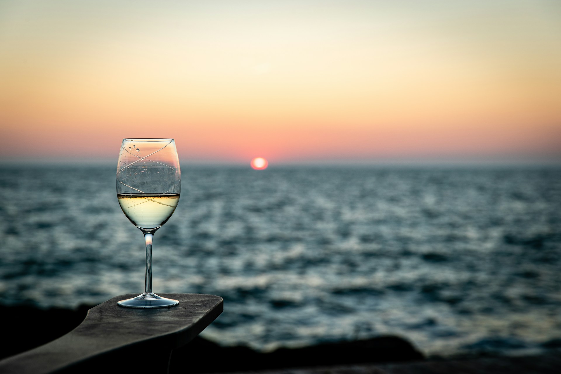 Wine glass overlooks the ocean sunset.
