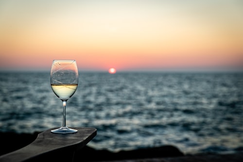 Wine glass overlooking the ocean at sunset