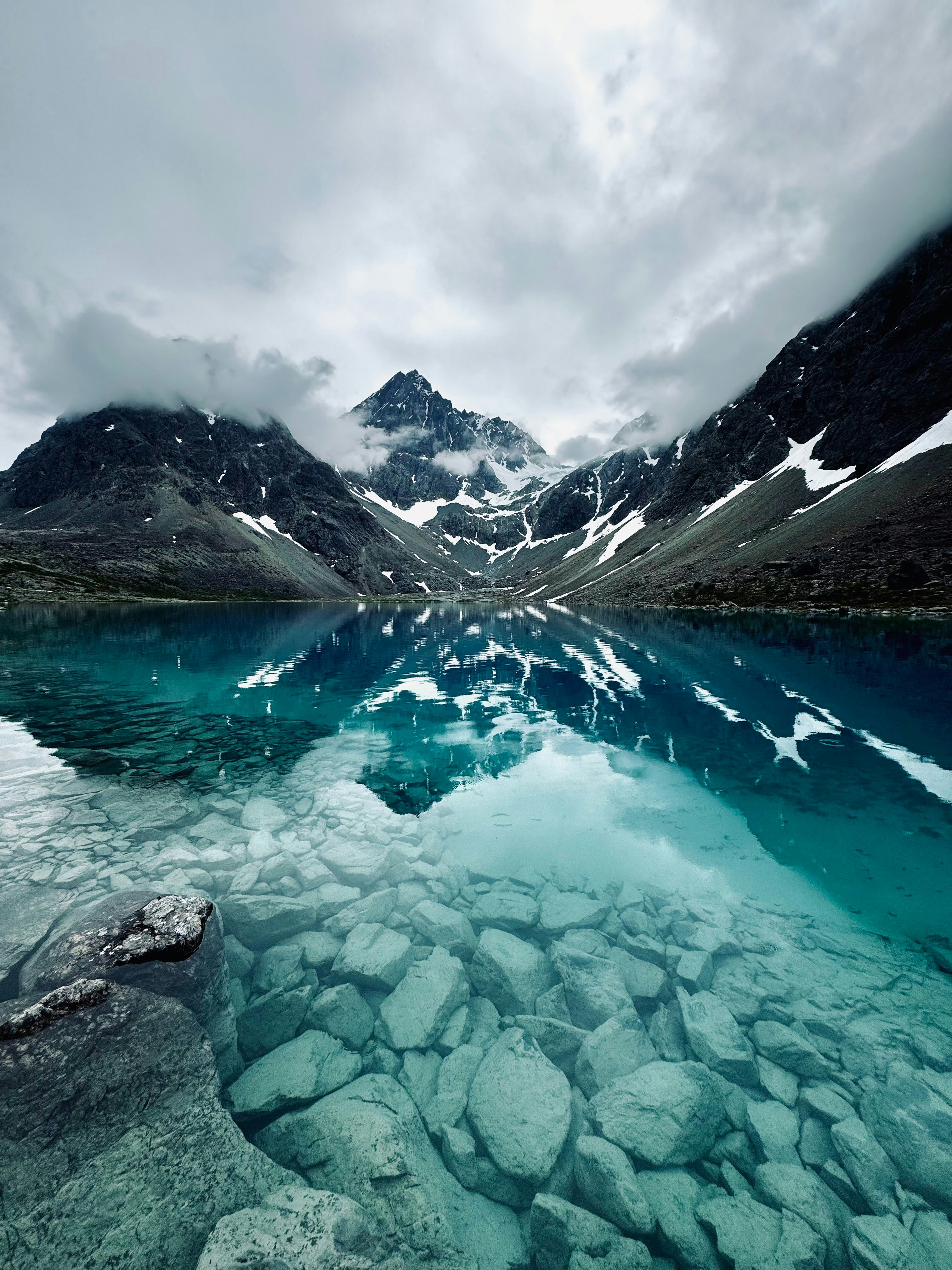 Verschneite Berge spiegeln sich im klaren, blauen See.