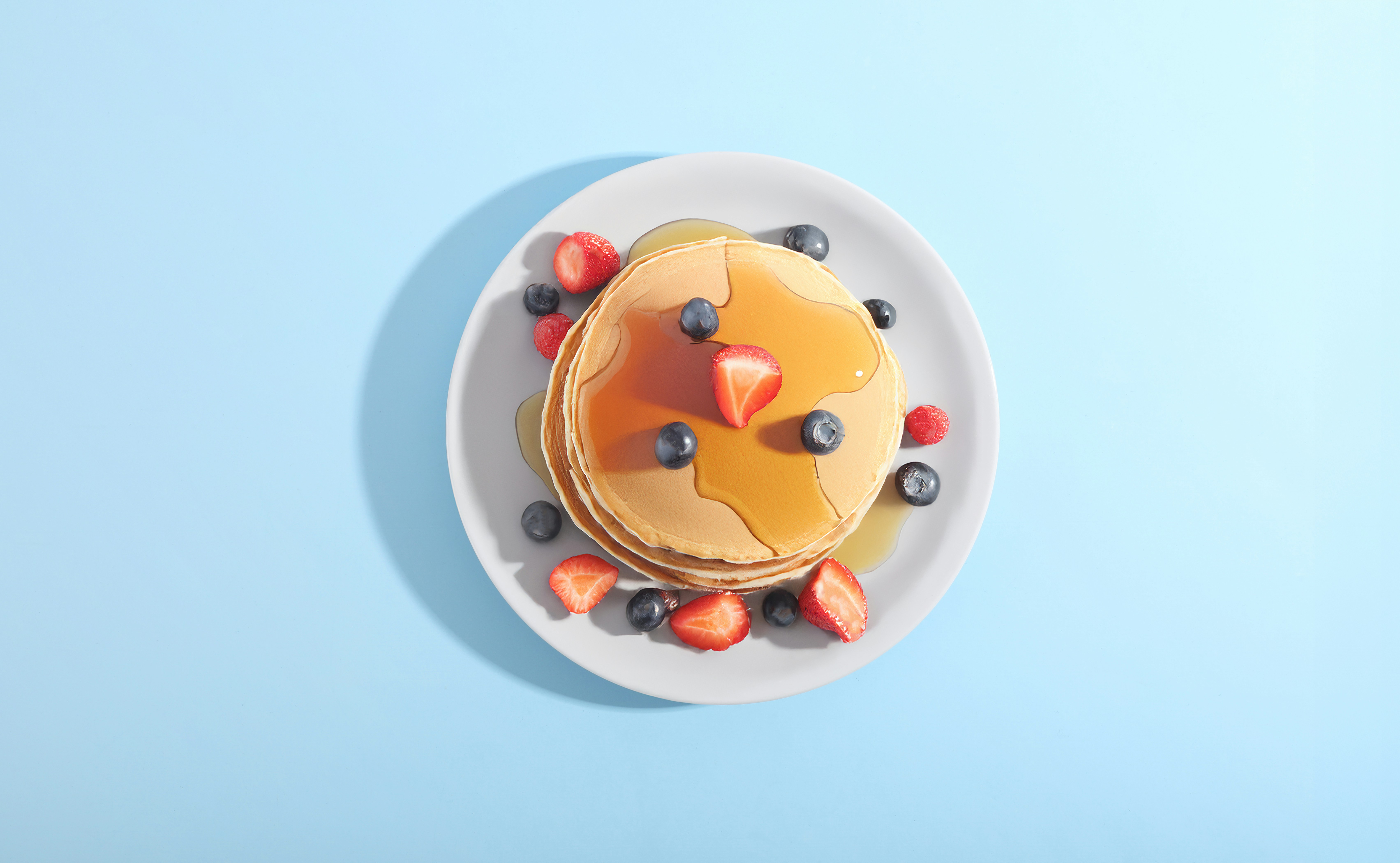 Pancakes with berries and syrup on a plate.