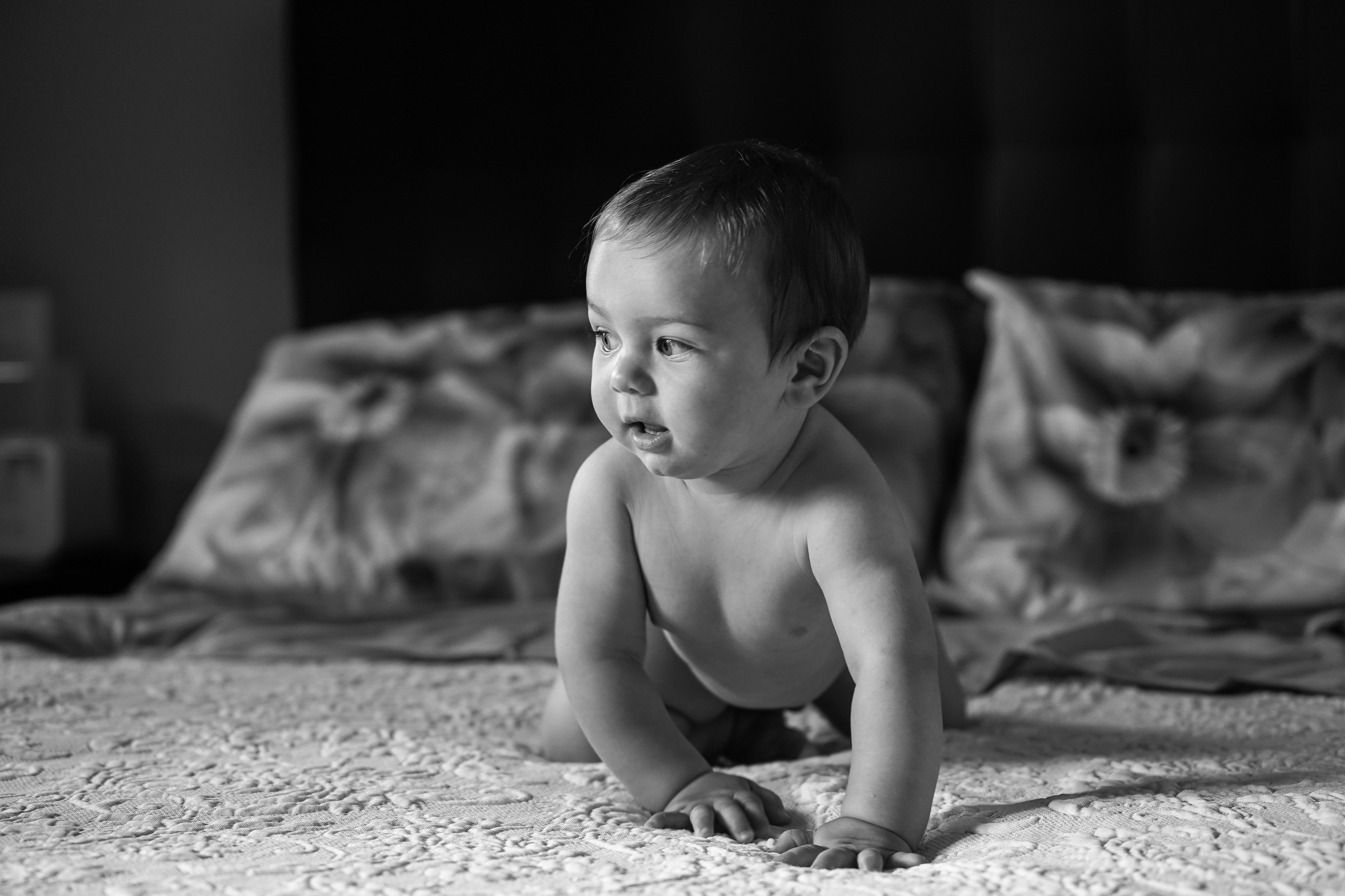 Curious baby crawling across a bed.