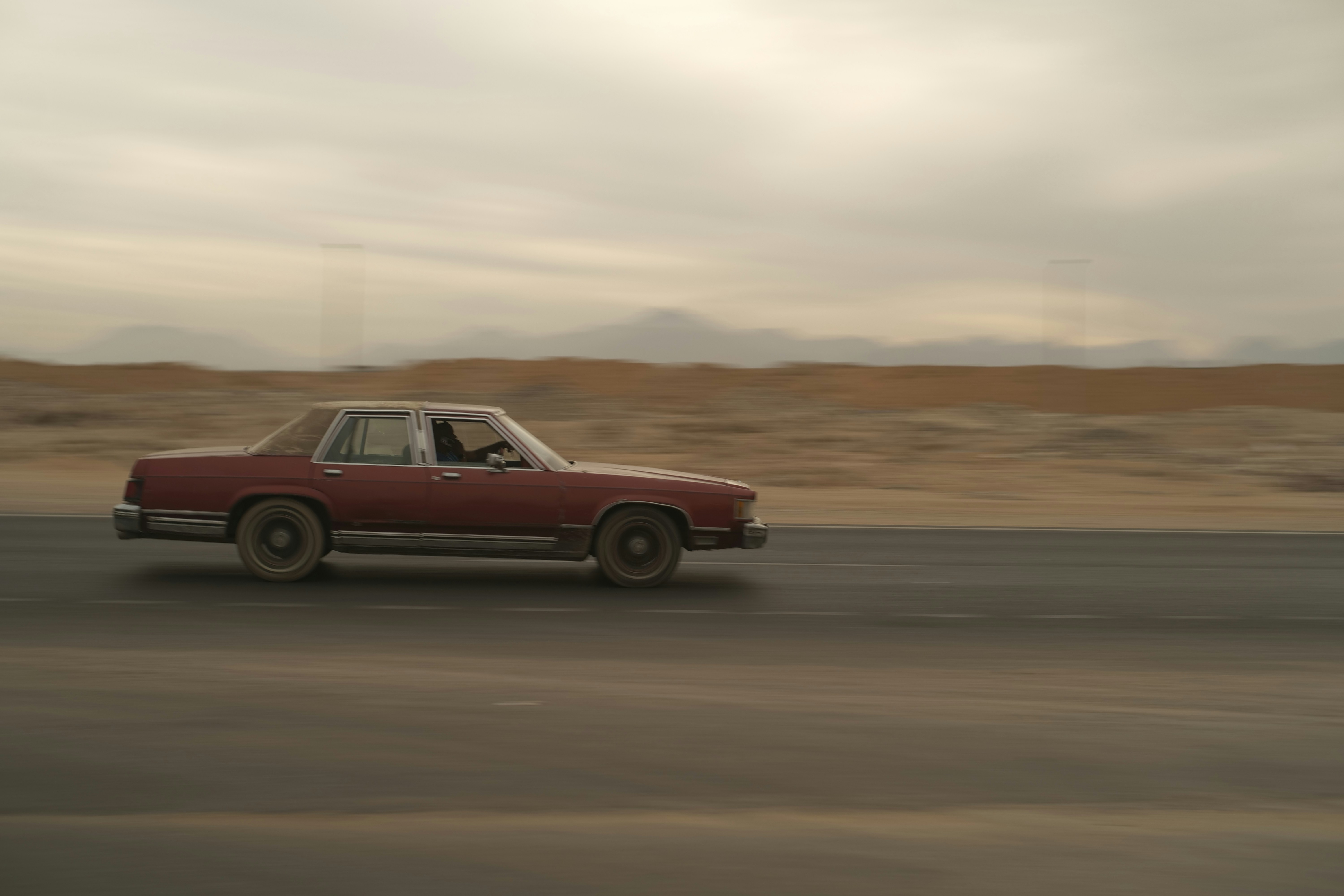 A car drives down a desert road.