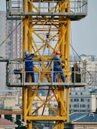 Construction workers working on a yellow crane.