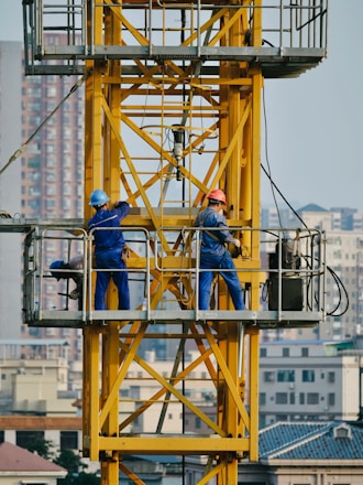 Construction workers working on a yellow crane.