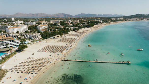 A picturesque beach scene with tourists and buildings.