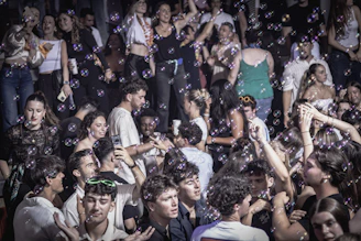 People are dancing in a crowded club with bubbles.