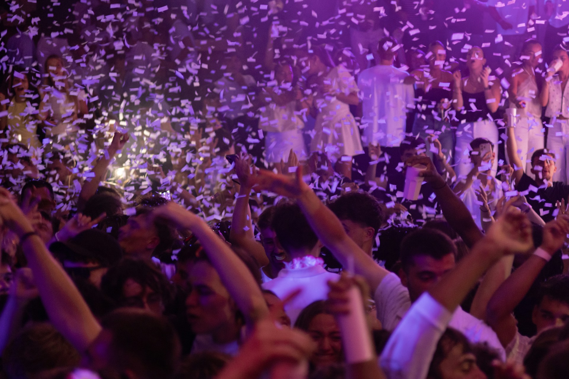 People party under confetti at a lively event.