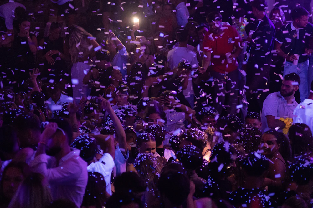 A crowd under purple light and confetti