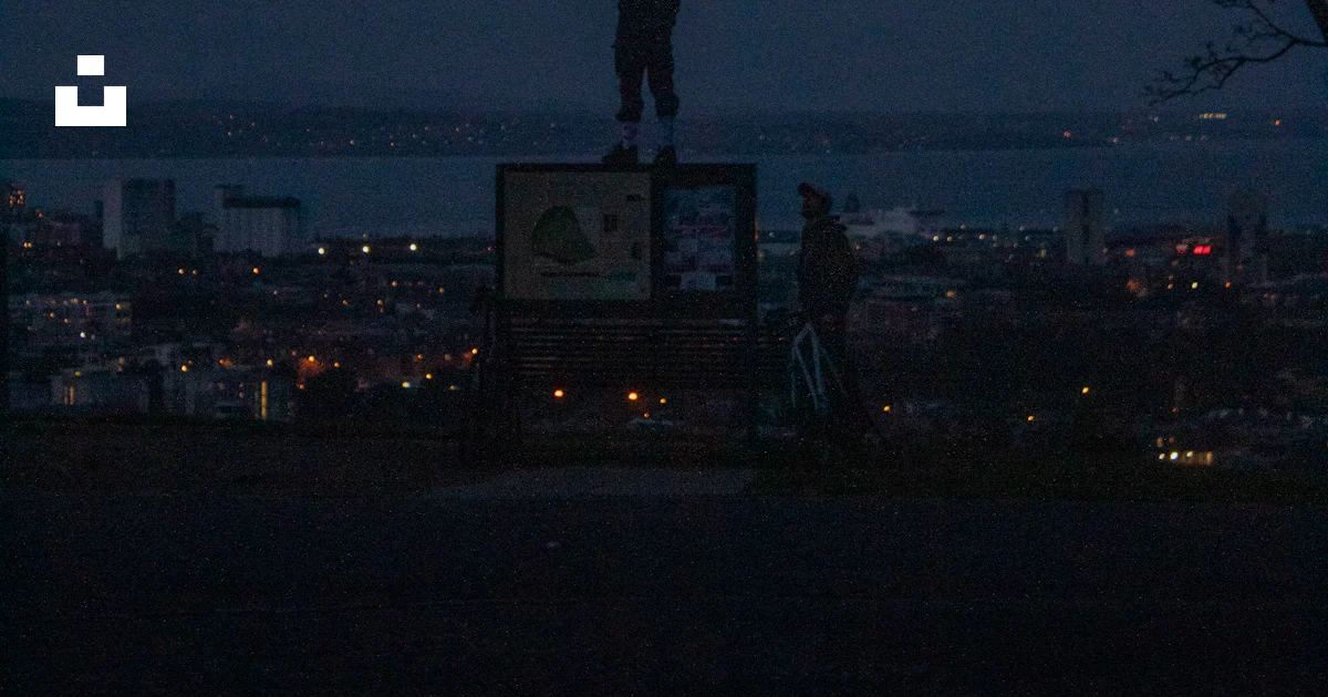 Overlooking Sign Person stands atop a sign overlooking a city at dusk. photo – Free ...