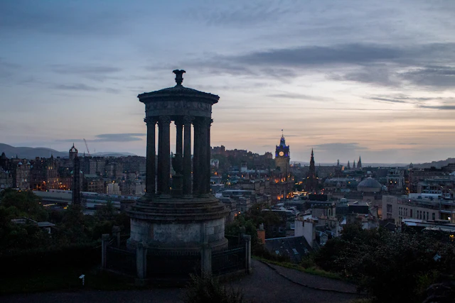 The Dugald Stewart Monument on Calton Hill at dusk with the city and castle skyline beyond