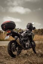 A motorcycle is parked beside a dusty road.