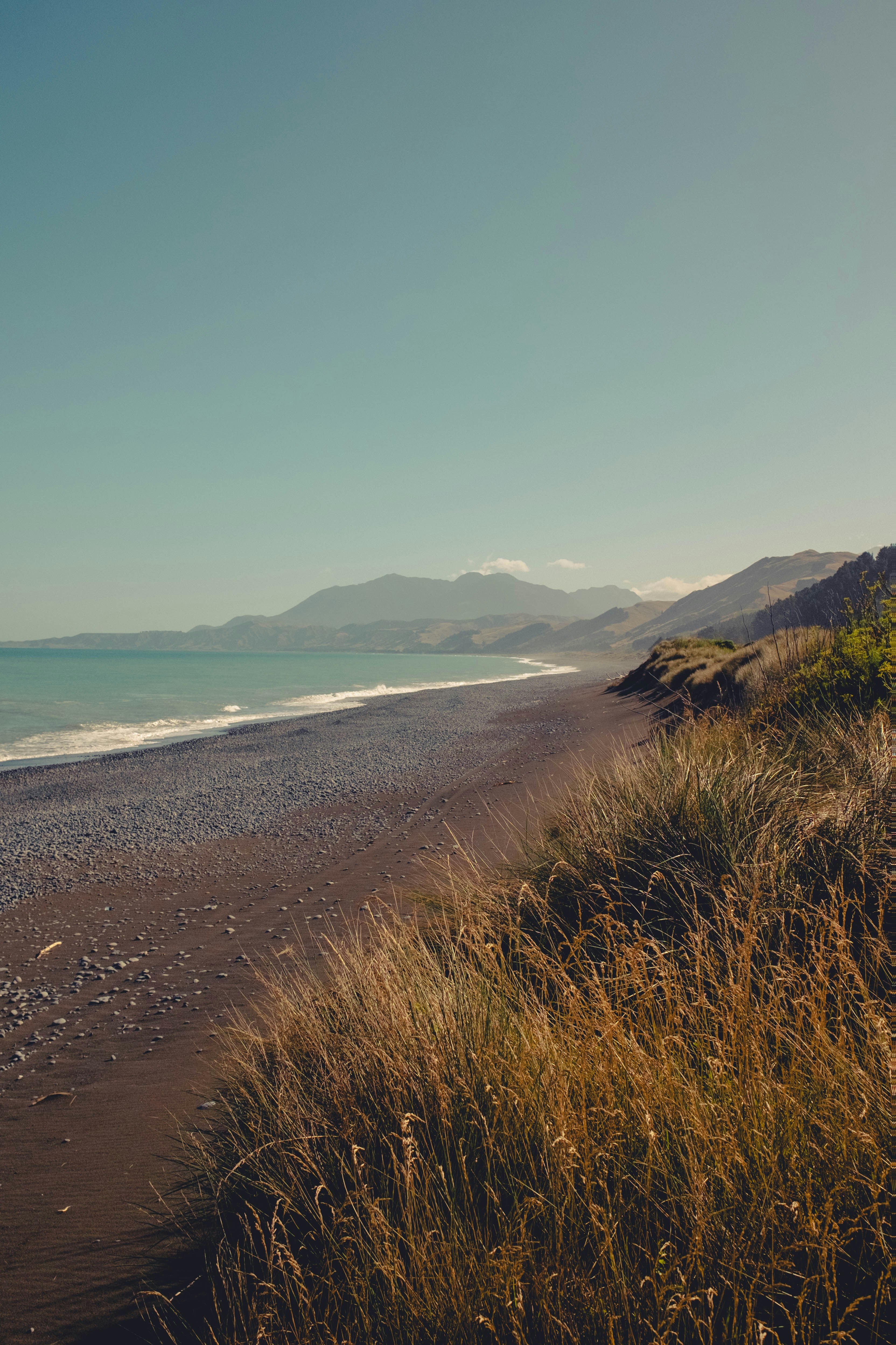 A serene beach scene with ocean and mountains.