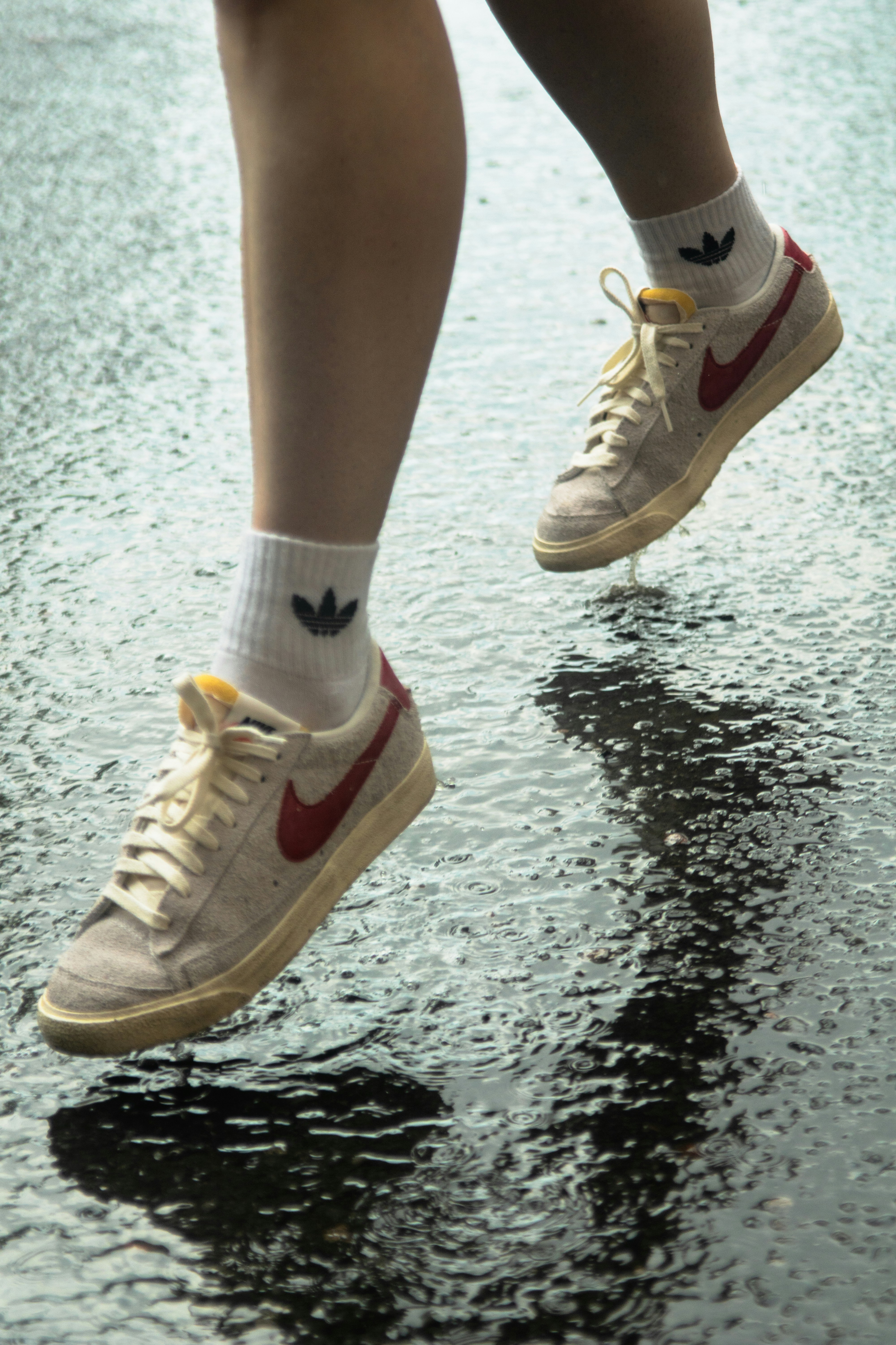 Close-up shot of a person’s feet in Nike sneakers bouncing over wet asphalt.
