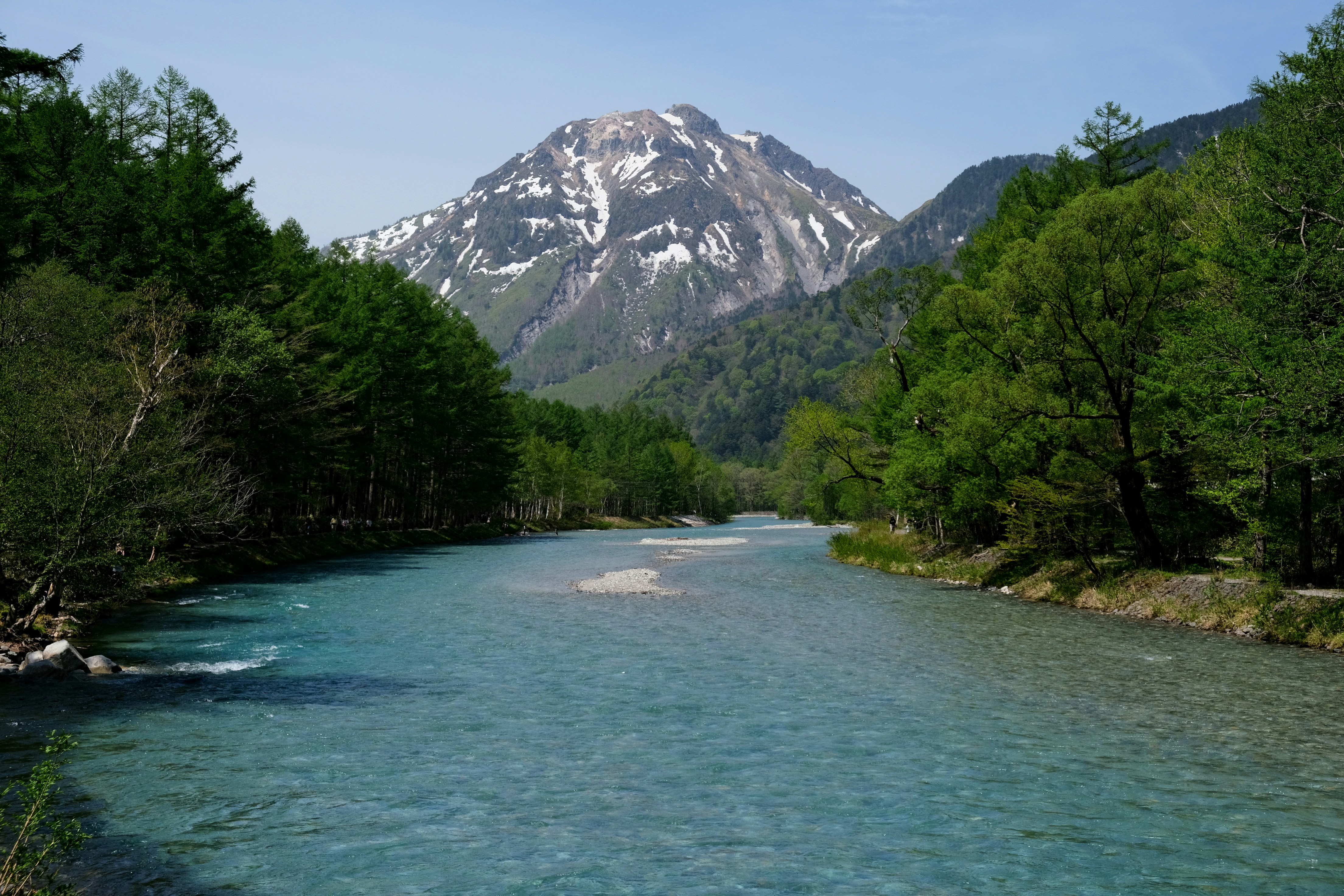 A river flows towards a snowy mountain.