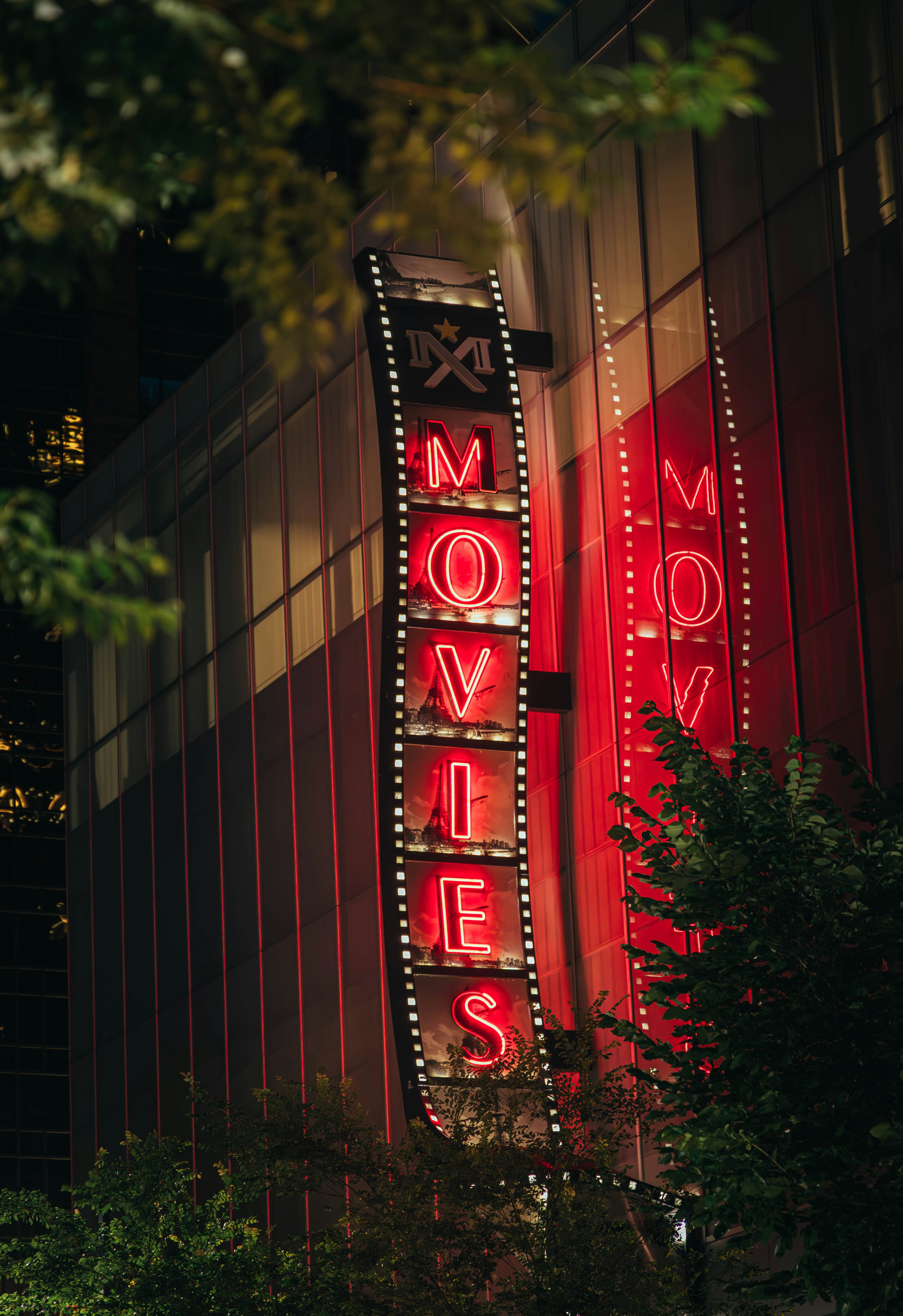 A neon "movies" sign lights up at night.