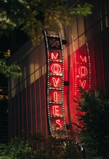 A neon "movies" sign lights up at night.