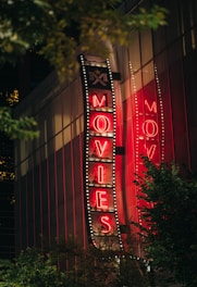 A neon "movies" sign lights up at night.