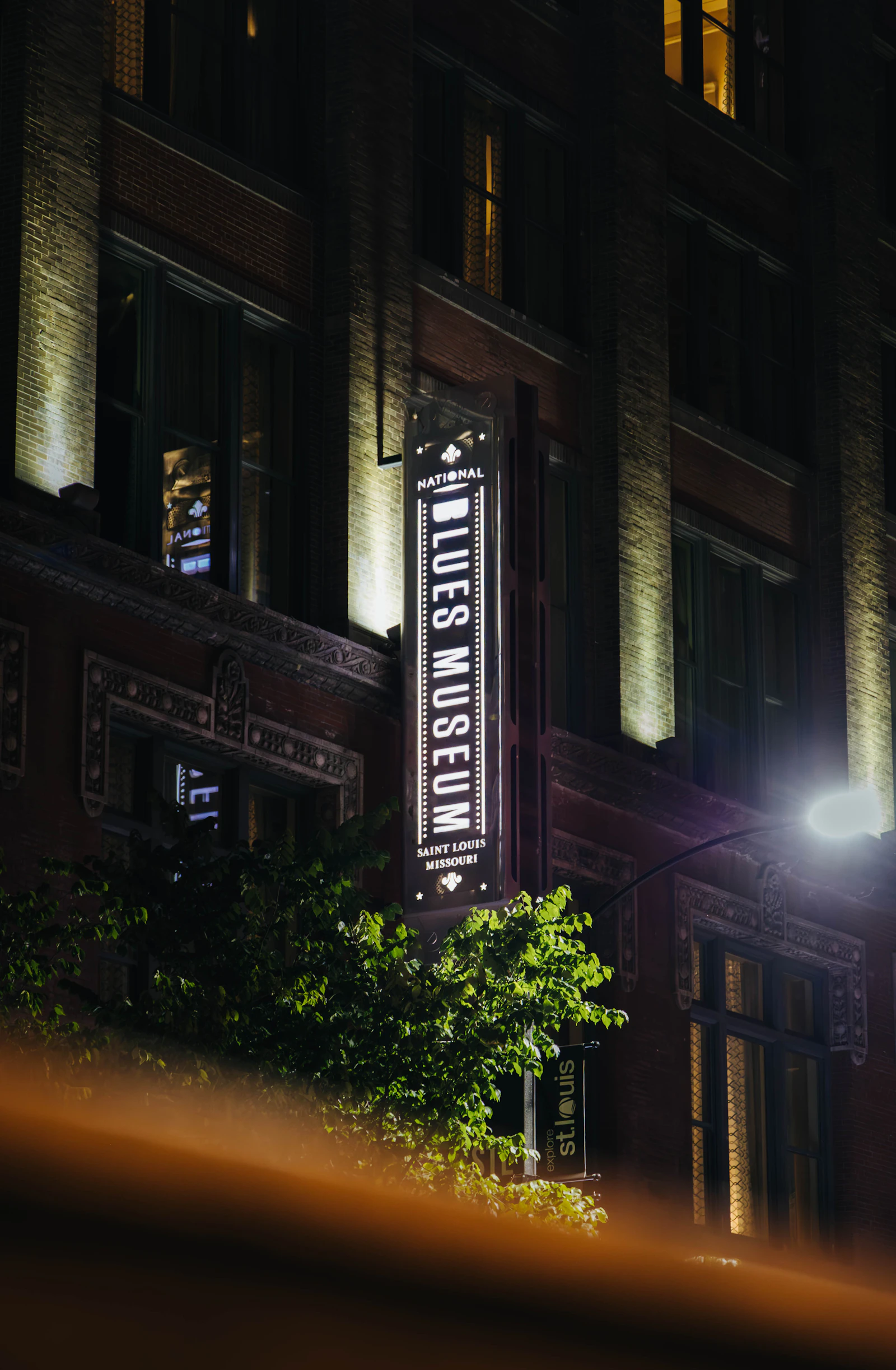 A lit brick facade at night in downtown St. Louis with a vertical sign reading Saint Louis Missouri