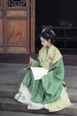 A woman writes while wearing traditional attire.