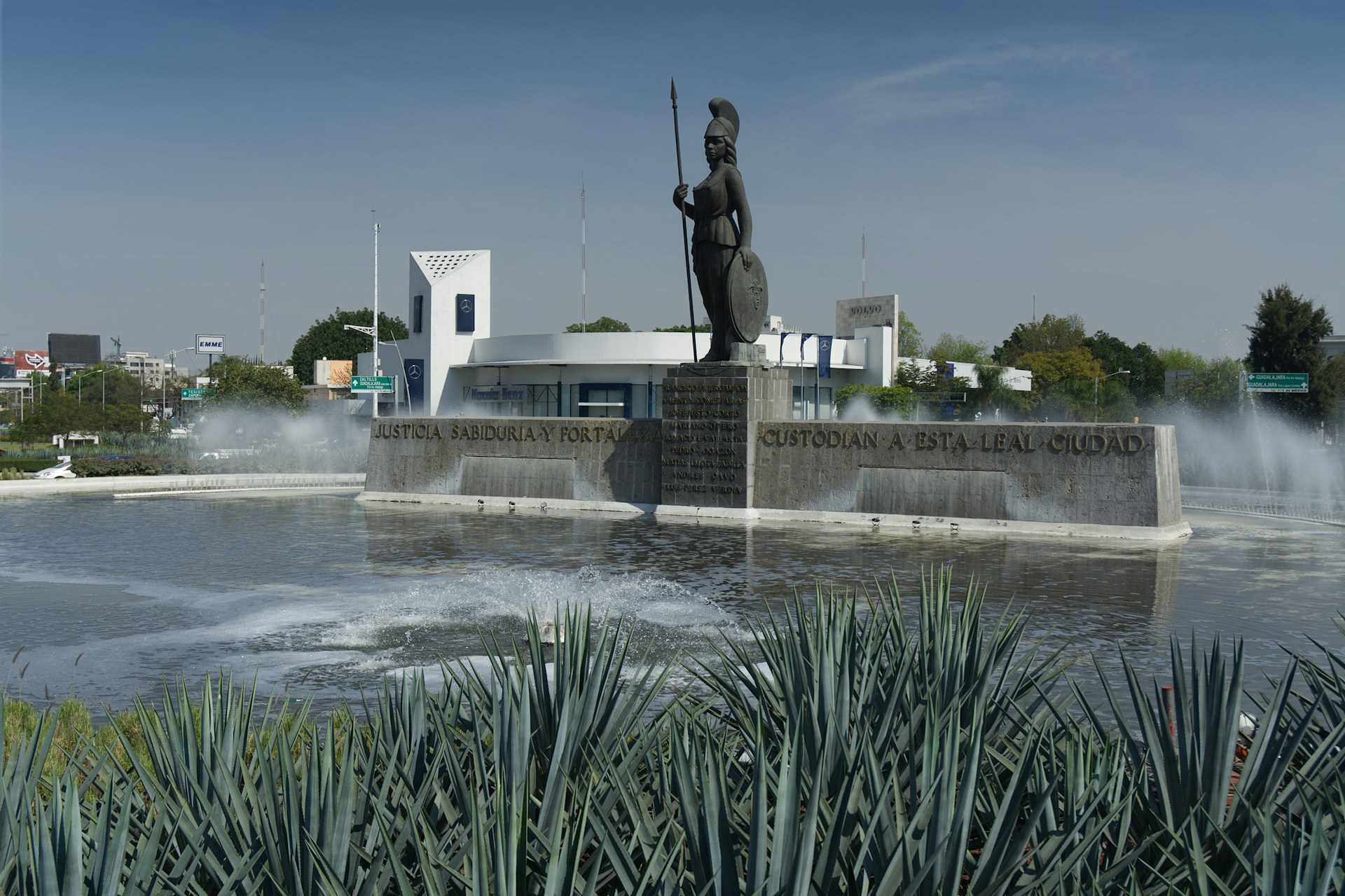 A statue stands above a fountain's splashing water.