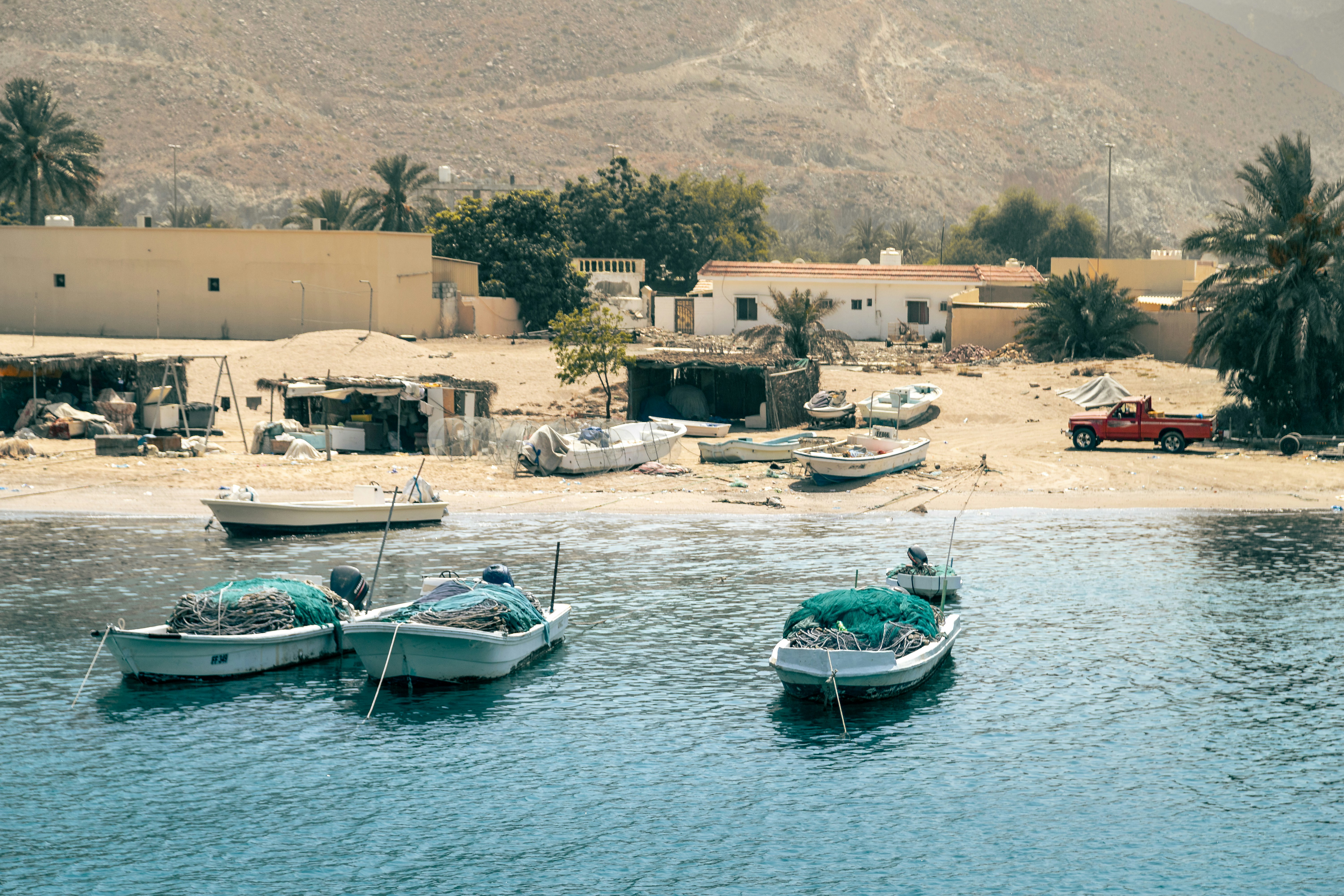 Boats rest on a beach near a coastal village.
