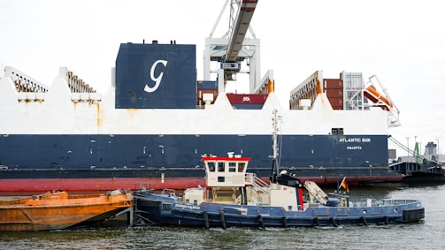 A tugboat works near a large cargo ship.