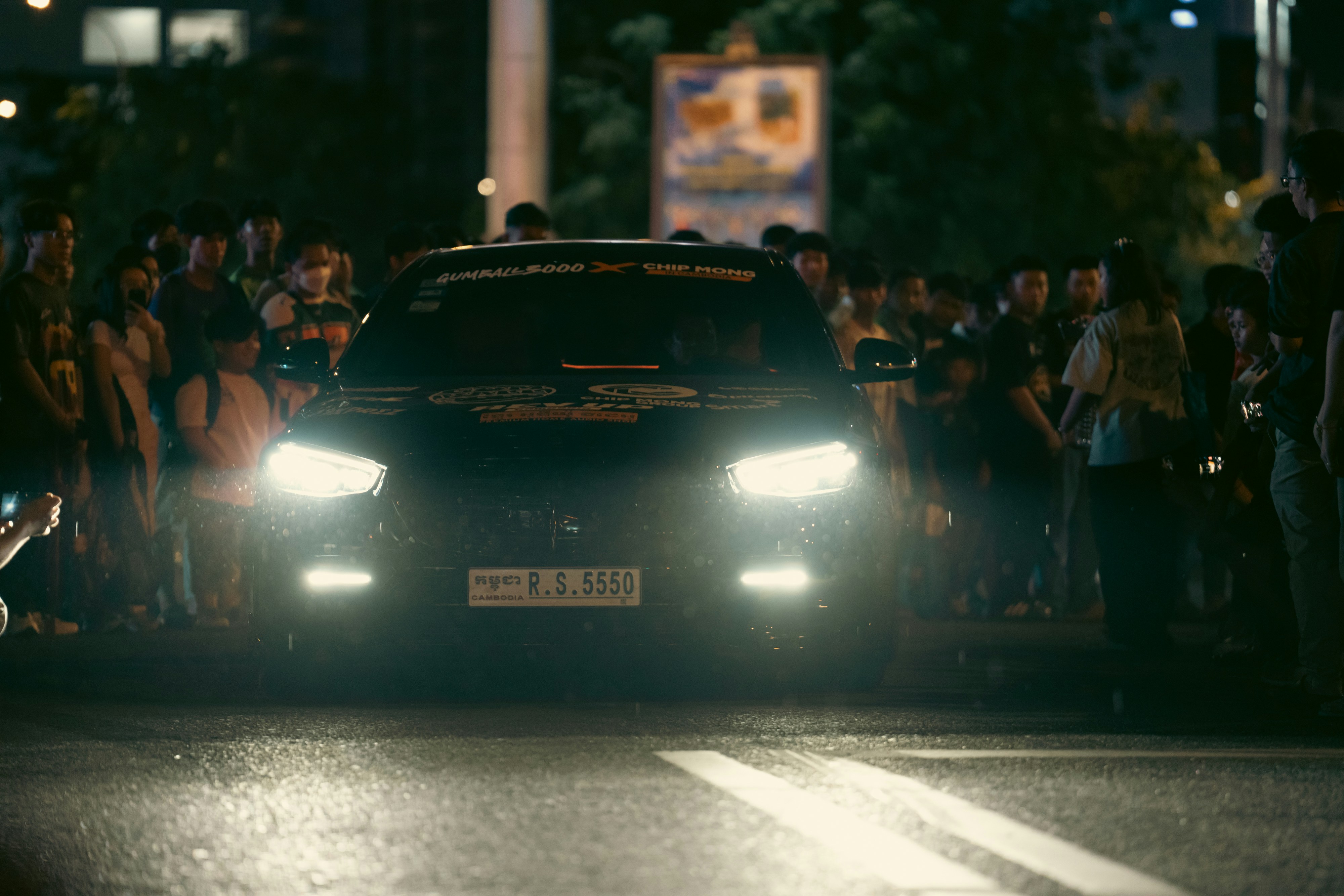 A car is surrounded by a group of people.