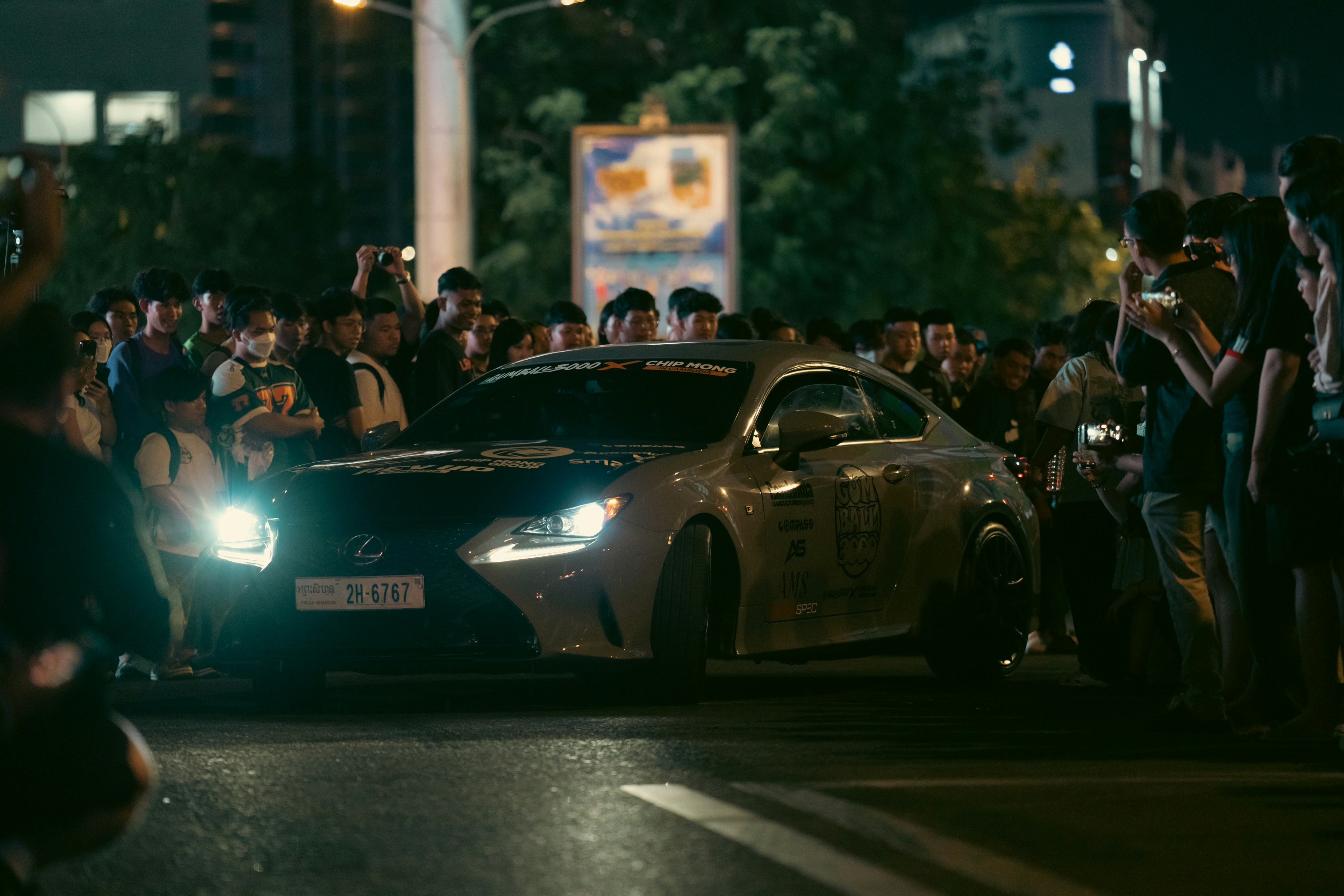 A car drives through a crowd at night. photo – Free Woman Image on Unsplash