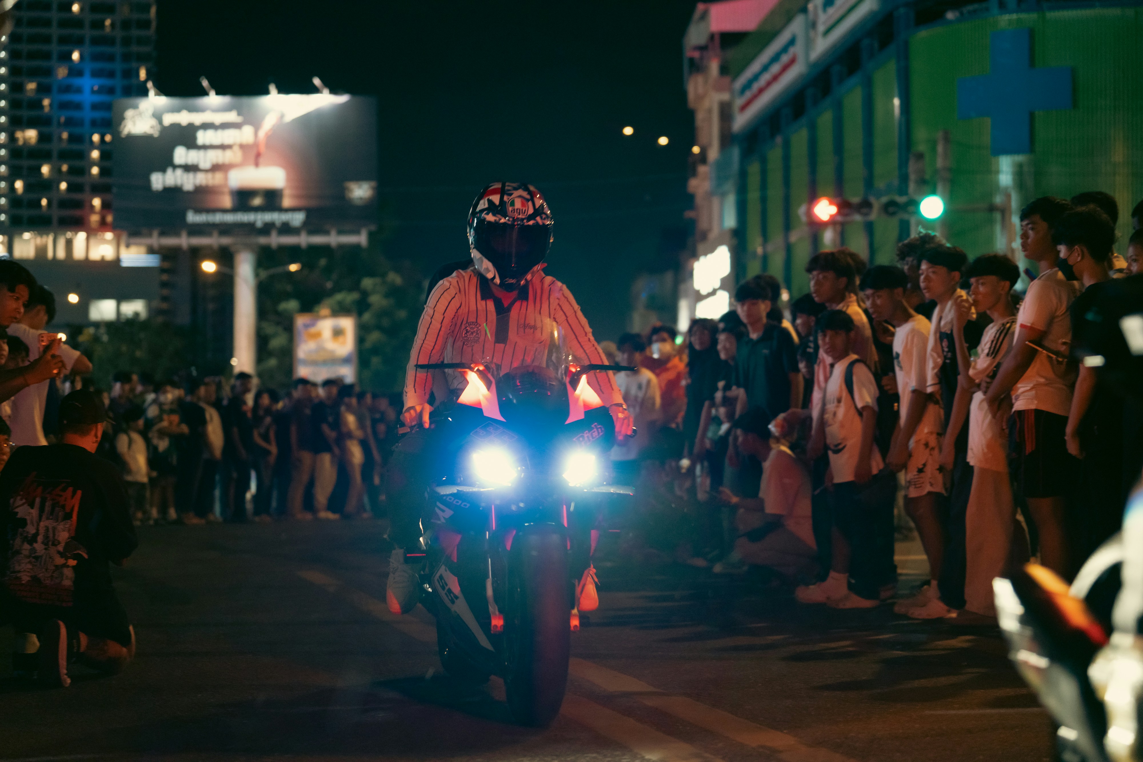 A motorcyclist rides through a crowd at night.