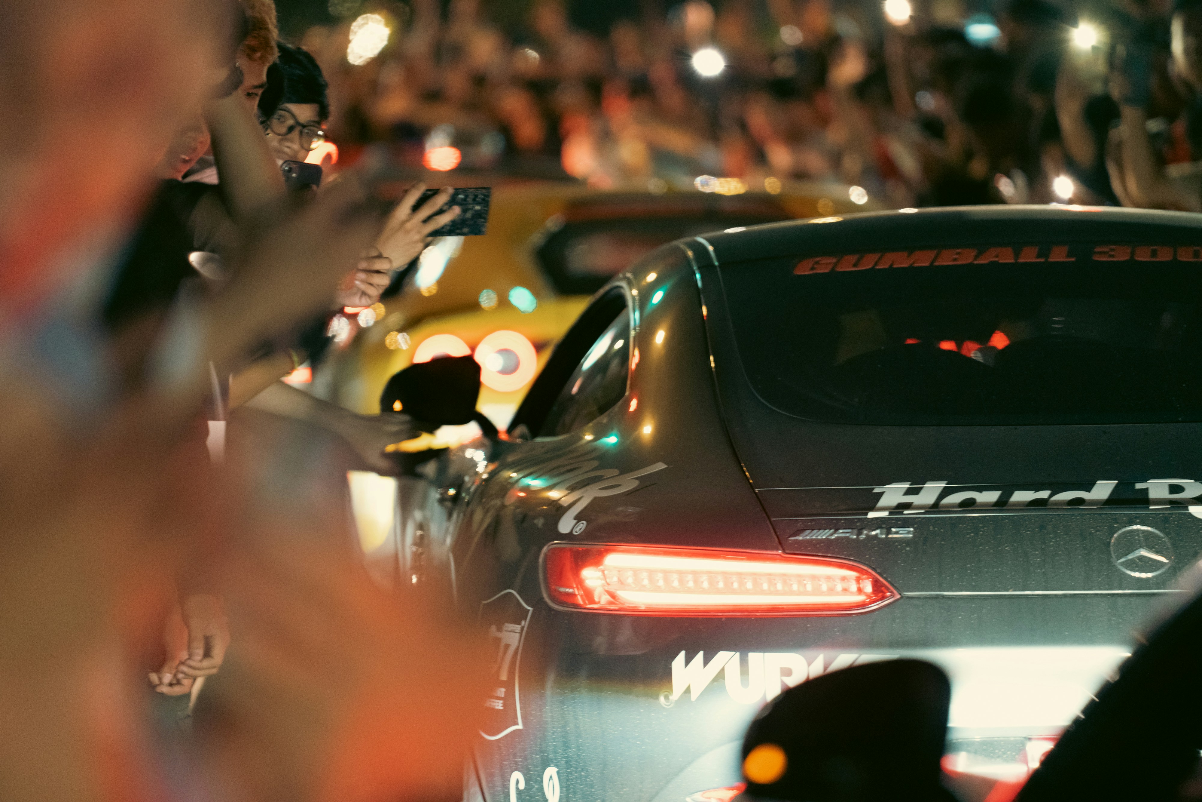 Fans surround a car during a nighttime event.