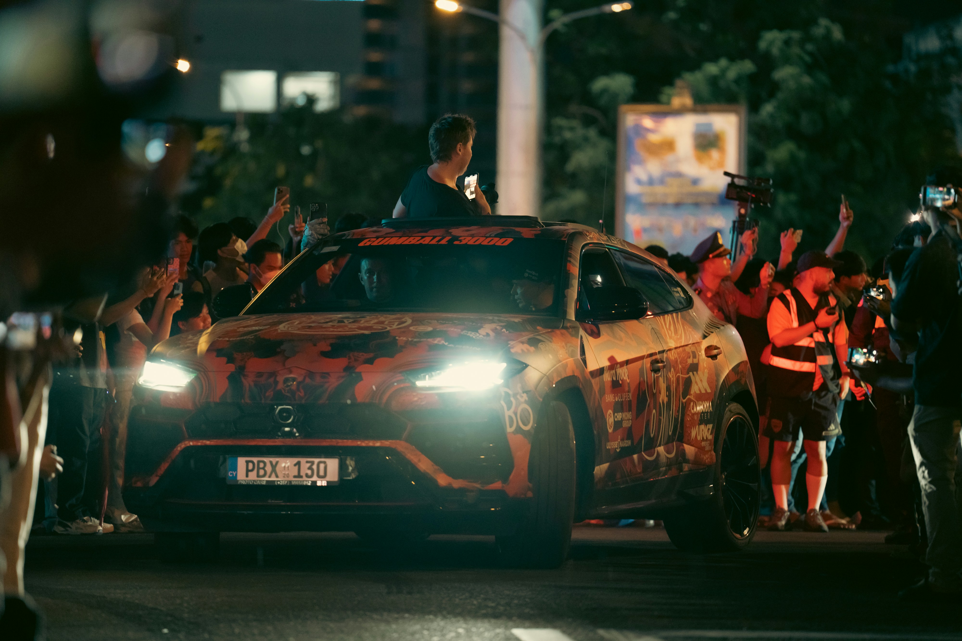 Fans celebrate a person in a car at night.