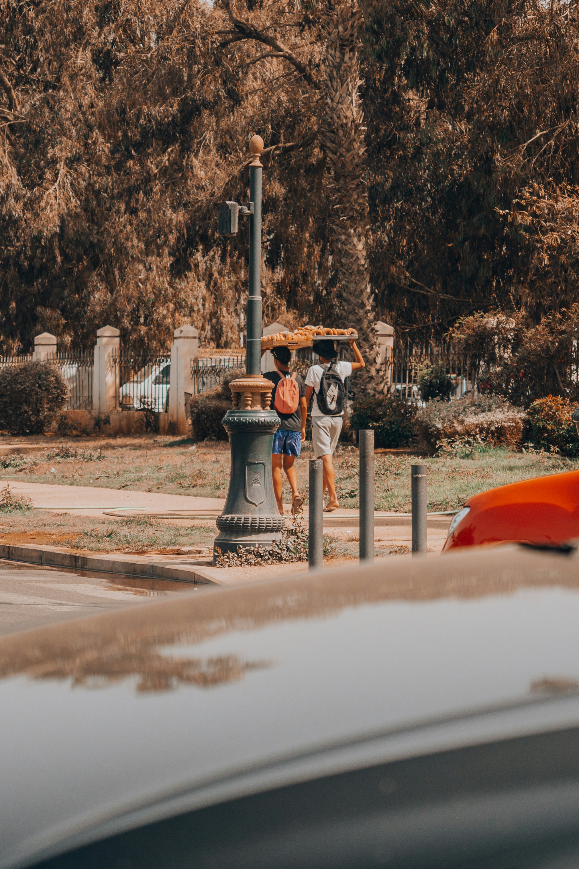 Two people walk carrying a load on their heads.