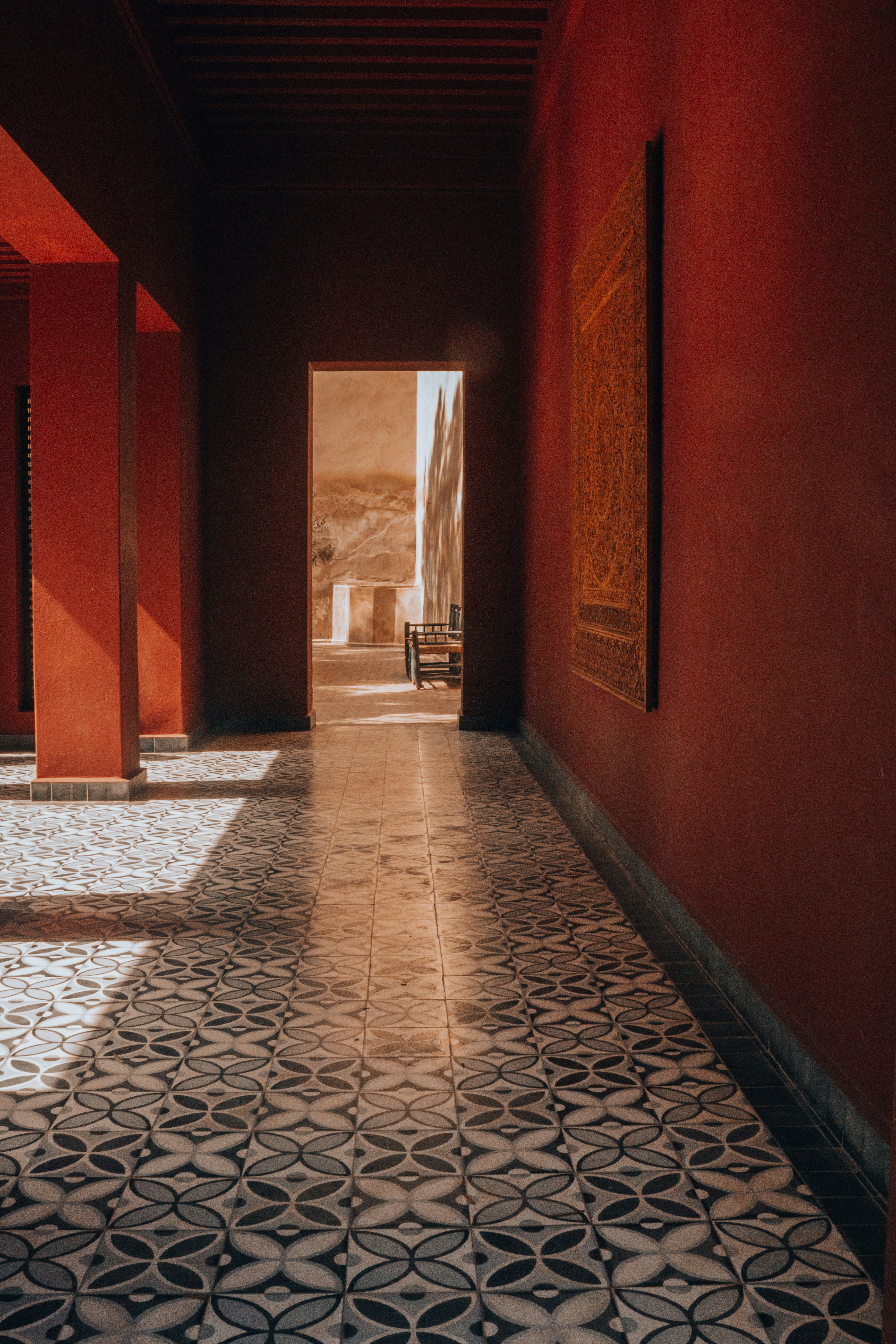 Red corridor with patterned floor leads to the outdoors.