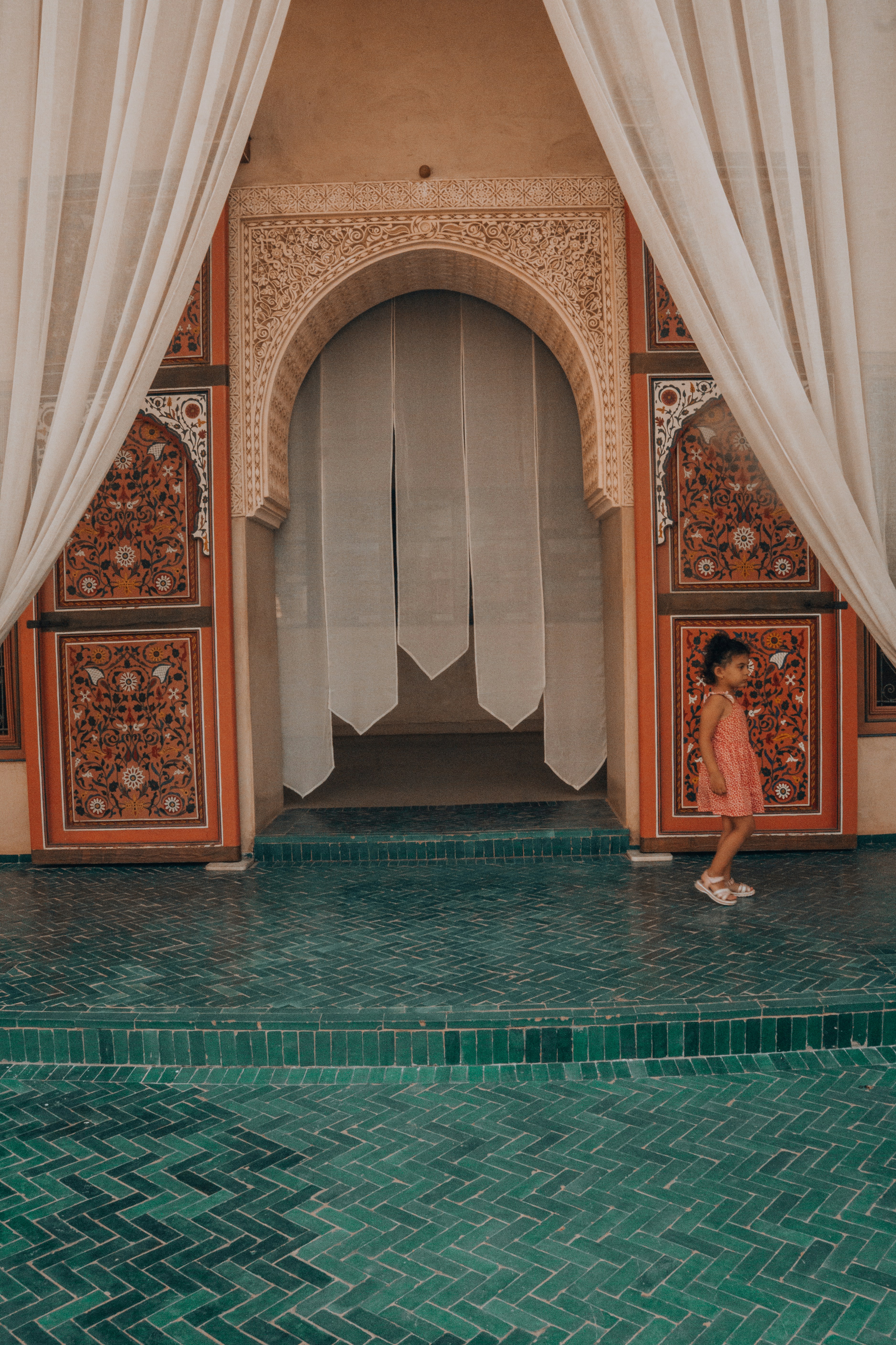 A young girl stands in an arched doorway.