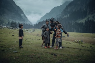 Children play in a valley surrounded by mountains.