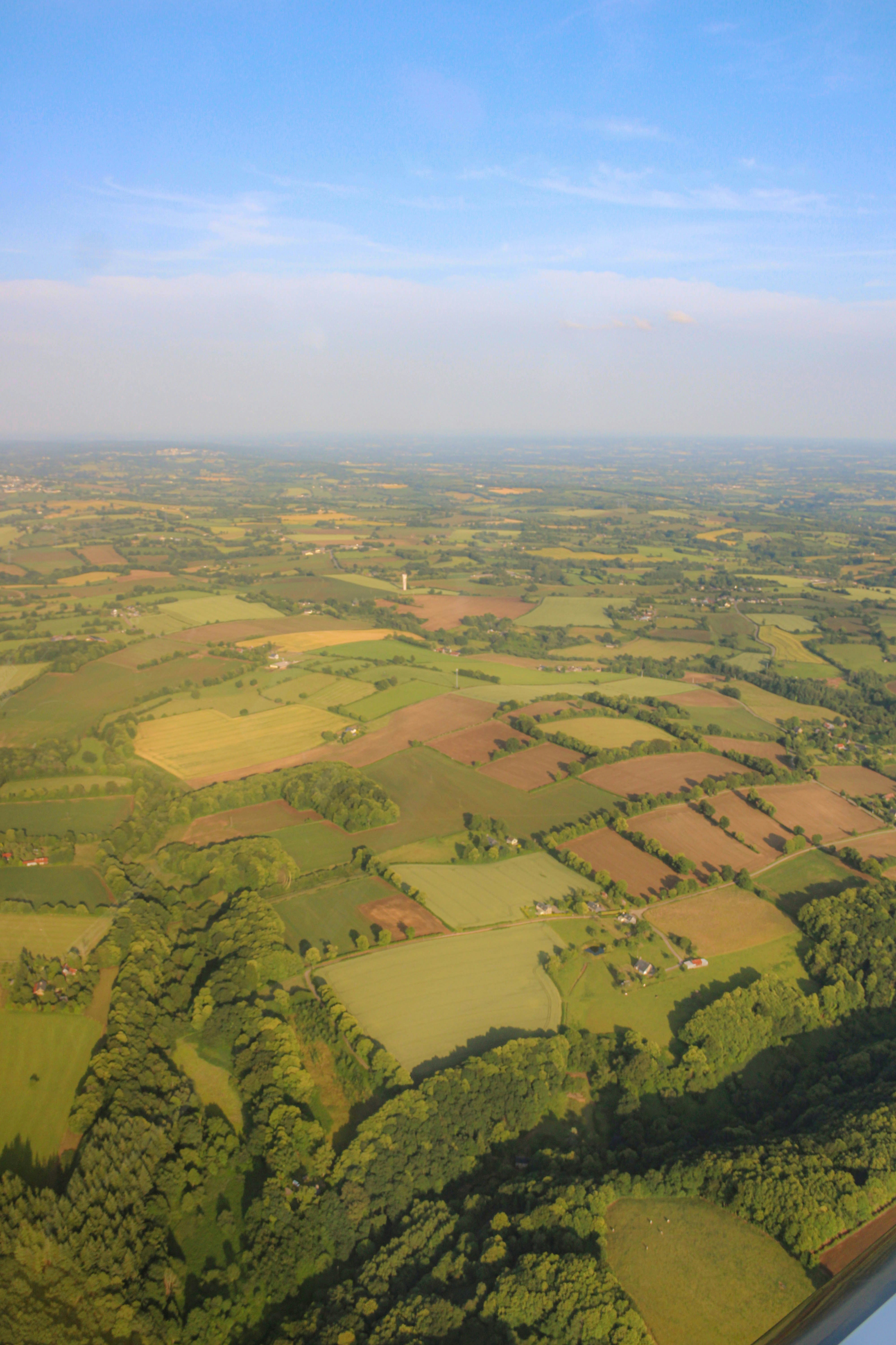 Aerial view: vast green fields and blue sky.