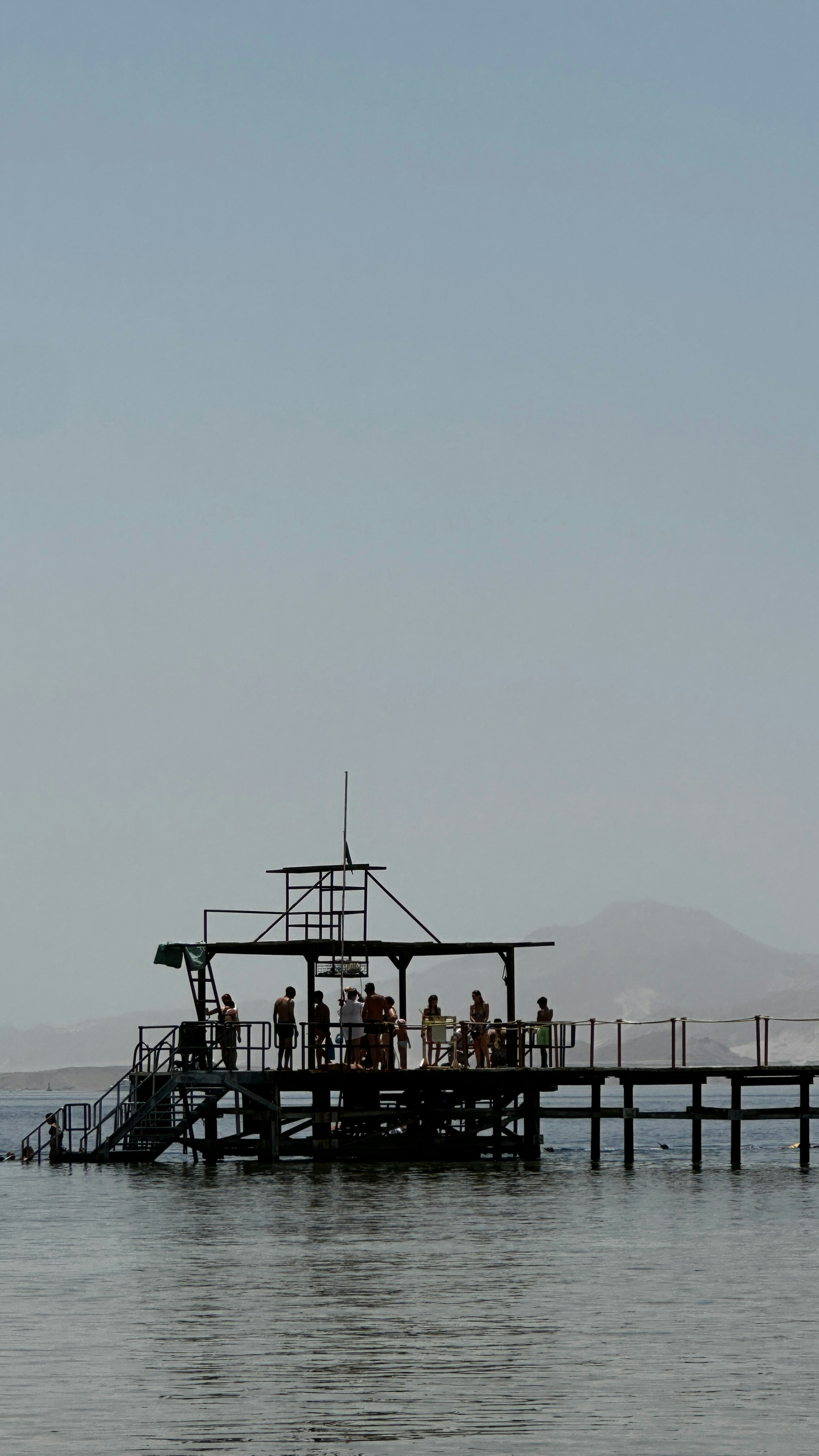 People stand on a pier over the water.