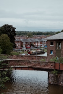 A brick bridge overlooks a canal and houses.