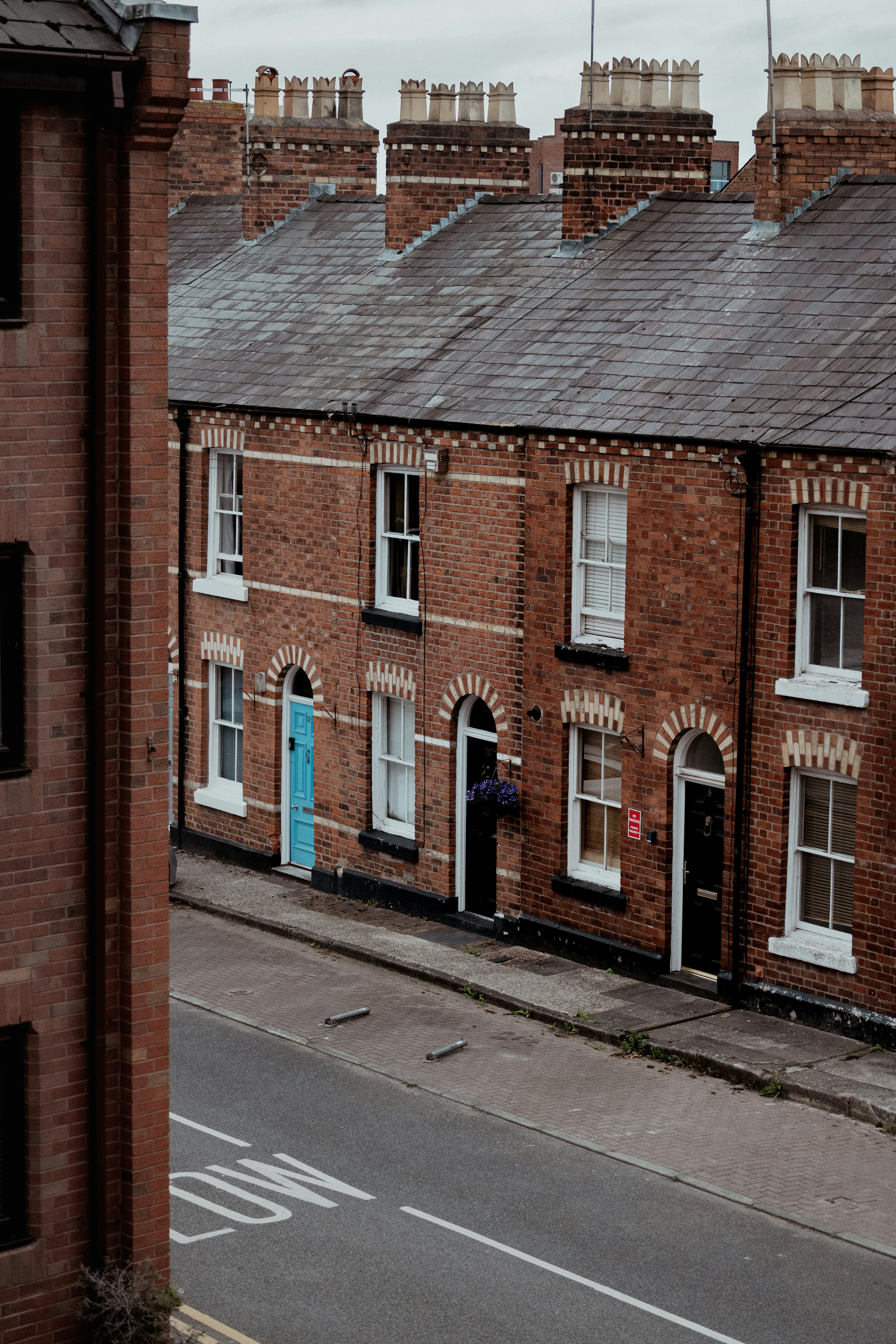 Row of brick houses with chimneys and a street.