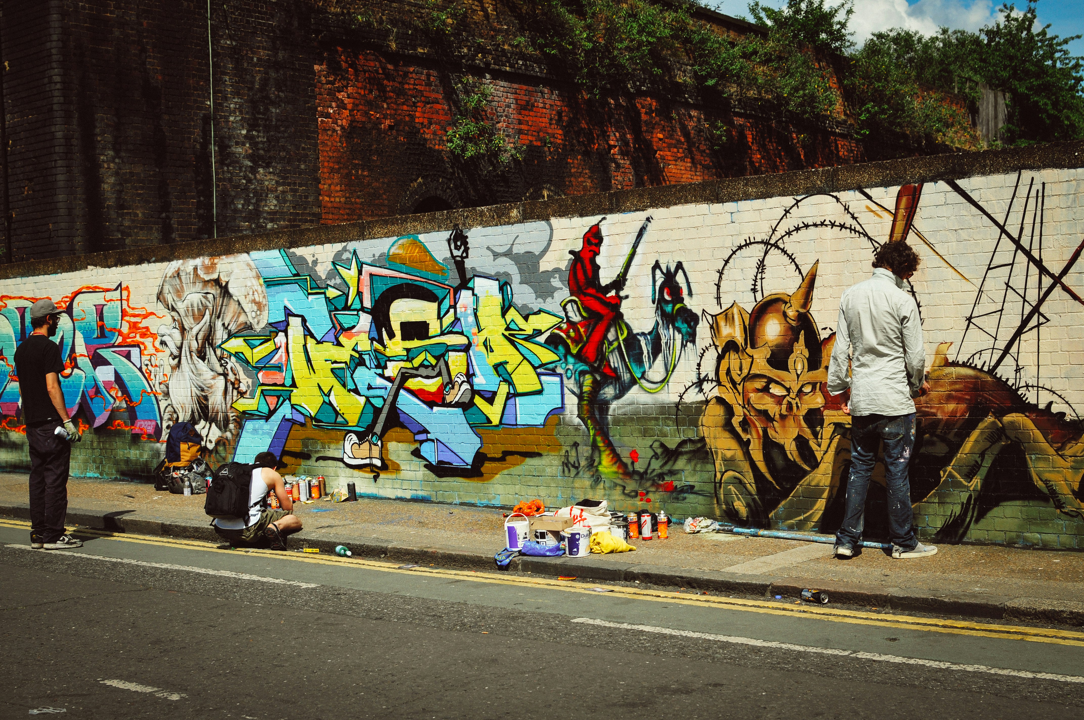 Artists create graffiti on a city wall.