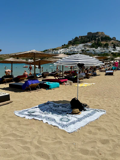 A sunny beach scene with umbrellas and sunbathers.
