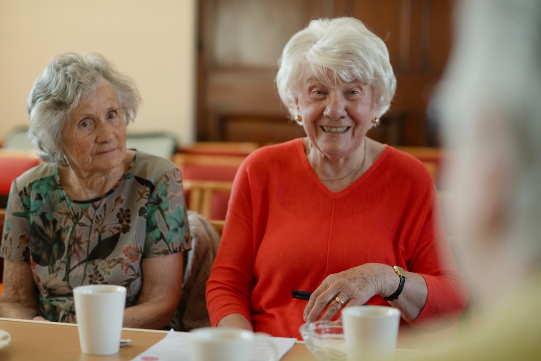 A friendly caregiver smiling and showing their credentials to a senior woman in a living room setting - pittsburgh home care agencies A friendly caregiver smiling and showing their credentials to a senior woman in a living room setting - pittsburgh home care agencies